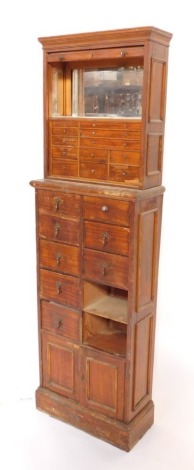 A late 19thC pine shop cabinet, the top section with tambour roll top, opening to reveal boxed interior with marble shelf and mirrored back, on an arrangement of ten drawers with star droplet handles and cupboard base, on a plinth base, 148cm high, 46cm w