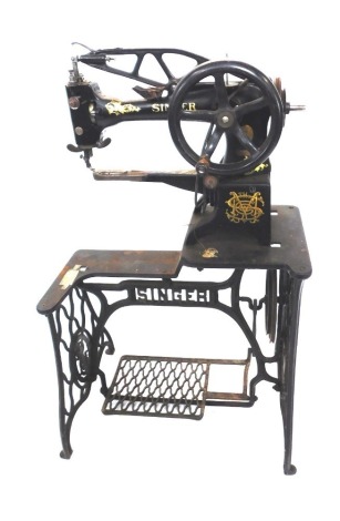 A late 19thC Singer industrial sewing machine on treadle base, cast treadle base, 115cm high, 65cm wide, 36cm deep.