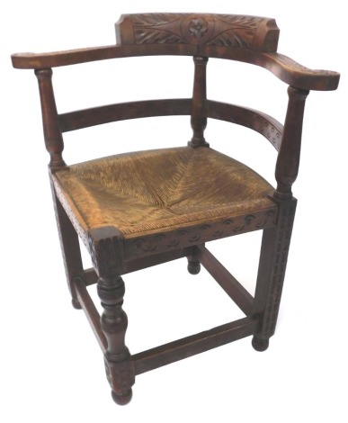 A late 19thC oak corner chair, the carved back and a square rush seat, on turned supports, with bun feet, 79cm high, 46cm wide, 45cm deep.