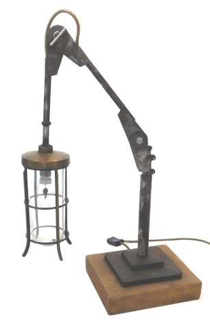 An industrial steel adjustable lamp, with brass lantern fitting, adjustable steel arm and a wooden base, 60cm high when arched, 22cm wide, 20cm deep.