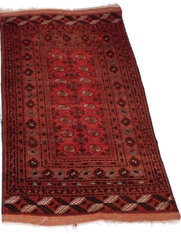 An Eastern red ground rug, with medallions and borders, with tassle ends, 197cm x 121cm.