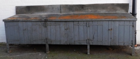 A workshop counter, with metal supports, with pine doors, all painted in grey, 115cm high, 316cm wide, 63cm deep.