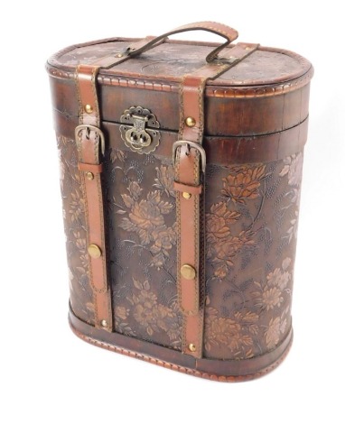 An Eastern floral applied wine bottle carrying case, with leather strap and buckle design, opening to reveal a lined interior, 30cm high, 26cm wide, 15cm deep.