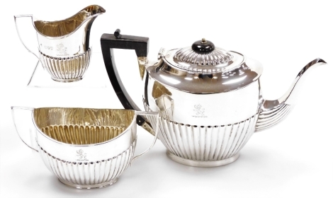 A Victorian silver three piece tea set, comprising teapot with ebonised knop and handle, two handled sugar bowl and milk jug, each with semi fluted body and engraved lion crest, Maxfield and Sons, London 1894, 32¾oz gross.