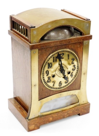 An early 20thC Art Nouveau oak and brass cased mantel clock for Liberty and Co, circular brass dial bearing Arabic numerals, German Hamburg American Clock Movement eight day movement with exposed bell strike, the case of arched and out swept form, with an