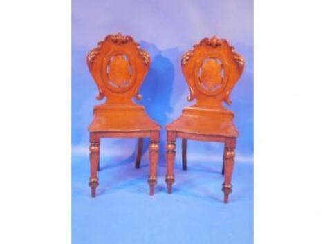 A pair 19th C oak hall chairs with scrolled shield backs on turned baluster legs