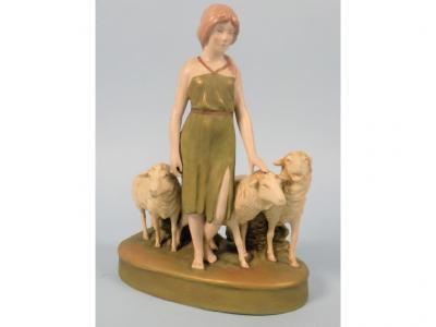 A Royal Dux group in the form of a lady beside three sheep on an oval base