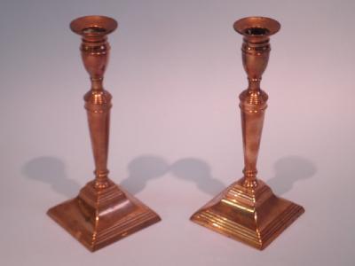 A pair of 19thC brass candlesticks each with tapering column square base