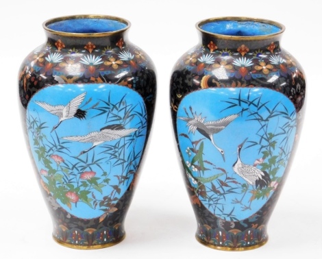 A pair of Japanese Meiji period cloisonne vases, of ovoid form, decorated with reserves of cranes, bamboo, and convolvulus, verso sparrows, wisteria and chrysanthemums, etc., against a background decorated with lion dogs, flowers, and foliate motifs, 31.5