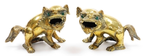 A pair of Chinese brass figures of dogs of fo, each inset with green paste stone eyes, 10cm high.