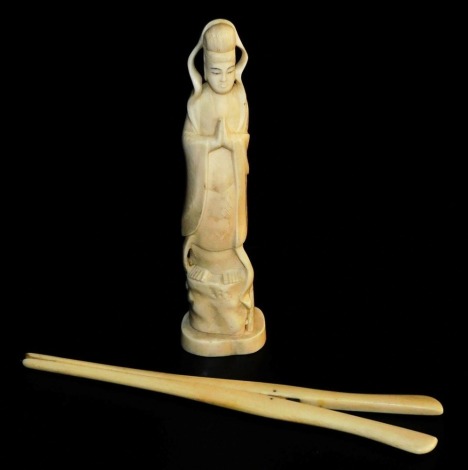 An early 20thC Japanese walrus ivory okimono, of a deity, signed to base, 18cm high (AF), and a pair of ivory glove stretchers, 20cm long (2).