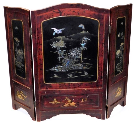 An early 20thC Japanese red and black lacquer three fold fire screen, with shaped top and three panels of flowering shrub and bird decoration, mother of pearl inlays, 91cm high, 94cm wide.