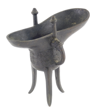 A Chinese bronze tripod libation cup of archaic form, with a geometric band and rectangular inscription tablet, 16.5cm high.