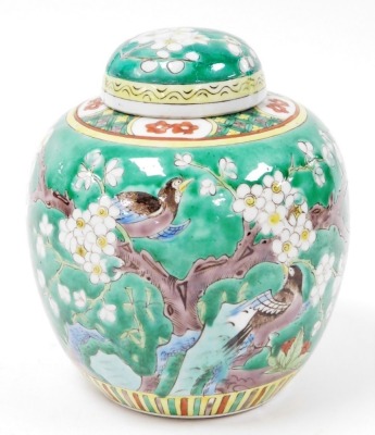 A 19th/ 20thC Chinese porcelain green enamelled ginger jar and cover, decorated with birds and prunus blossom, with hatched and reserved floral border, four Kangxi character mark, 19.5cm high. (AF)