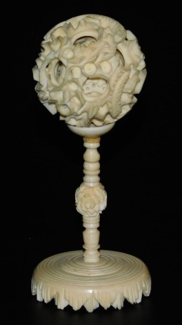 A Chinese early 20thC ivory puzzle ball on stand, with concentric balls, the outer ball carved with a dragon, 11cm high, the ball 4cm dimater.