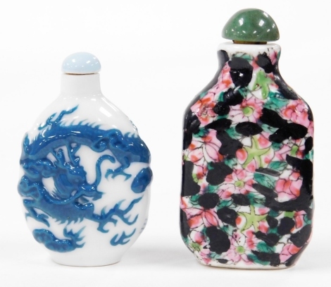 A Chinese porcelain snuff bottle, decorated in relief with blue dragon chasing a flaming pearl, 6cm high, together with a black and pink snuff bottle and stopper, decorated with blossom, two character mark, 7cm high. (2)