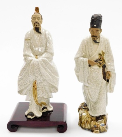 Two Chinese terracotta and white crackle glazed "mudmen" figures, including a figure of a man holding a branch, standing on a rock, 37cm high, a further figure of an official with hat, on wooden stand, 35cm high. (2)