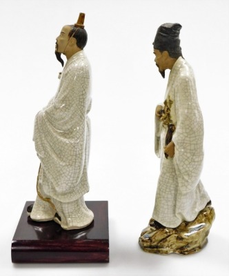 Two Chinese terracotta and white crackle glazed "mudmen" figures, including a figure of a man holding a branch, standing on a rock, 37cm high, a further figure of an official with hat, on wooden stand, 35cm high. (2) - 2