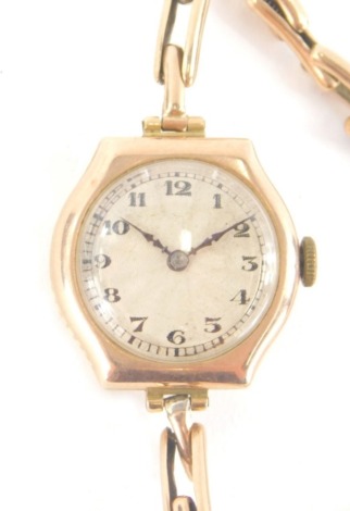 An early 20thC gold cased cocktail watch, in a shaped case with 2cm Arabic dial with an elasticated bracelet, 15g all in.