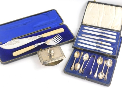 A George V silver topped desk blotter, of rectangular form with plain knop, probably Birmingham 1913, 10cm wide, cased fish serving set, plated teaspoons with bead outline, a cased set of entree knives. (a quantity)