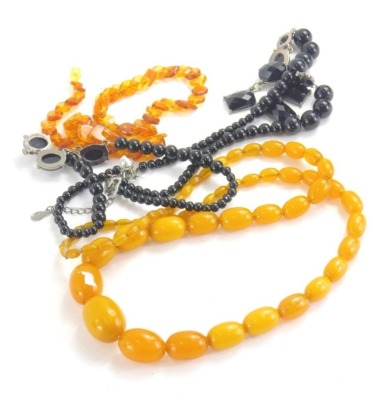 A graduated faux amber necklace, butterscotch colour, 70cm long and a quantity of other beads and necklaces. (3)