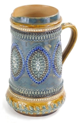 An early 20thC Doulton Lambeth stoneware jug, raised with ovals, flowers, and orbs, with a floral handle predominantly in blue and brown, impressed rosette mark beneath, 21cm high.