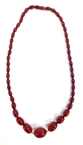 A red amber graduated necklace, the largest bead 3cm, smallest bead 1cm, approximately 41 beads, on a string strand, 66cm long overall, 46g all in.