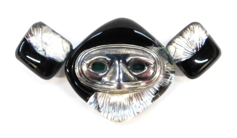 A J Gautier 1960/70s brooch, with applied glass detailing, in black an silver, with a raised silver face, with green eyes, on single pin back, 8cm wide, 38.6g all in.