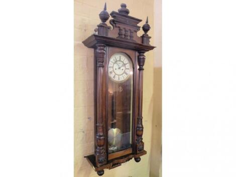 A Vienna wall clock, the walnut case with turned finials, with an enamel dial, 109 cm high