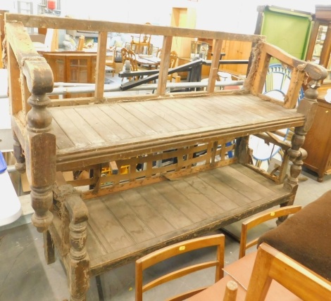 A pair of Victorian pine waiting room or club type benches, each with shaped arms, on turned legs, 194cm wide. (AF)