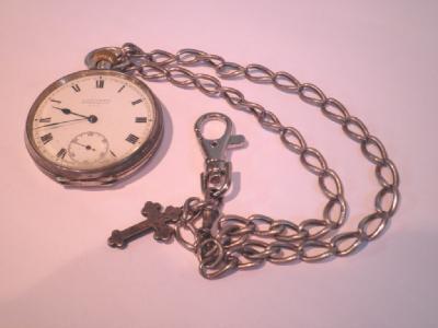 An engine turned continental silver pocket watch and chain with a cross pendant