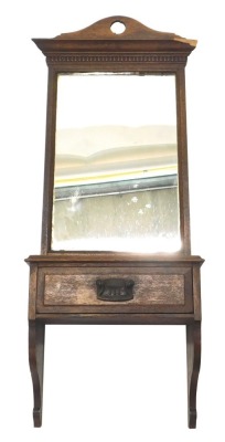 An early 20thC oak mirror, with a pierced shaped crest, rectangular plate above a drawer and two brackets, 80cm high, 35cm wide. (AF)