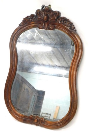 A hardwood cartouche shaped wall mirror, with a scroll carved crest, 80cm high, 52cm wide.