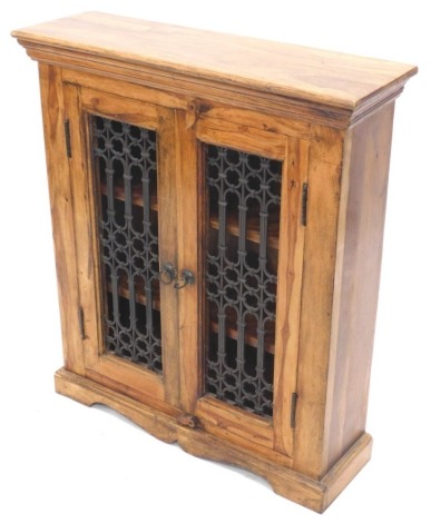 An Eastern hardwood side cabinet, with two doors, each with metal grills, on a shaped base, 85cm high, 74cm wide, 23cm deep.