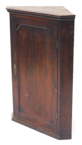 A 19thC oak hanging corner cabinet, with a panelled door, 108cm high, 75cm wide, with key.