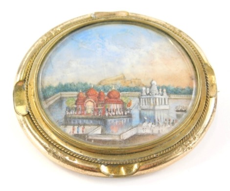 A 19thC Indian brooch, inset with an oval miniature of a temple, and an engraved back, All My Love Eric, 22/4/46, in a yellow coloured metal mount, 6cm wide.