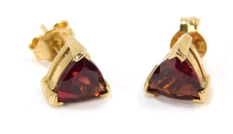 A pair of 9ct gold ruby stud earrings, each with triangle cut ruby, in claw setting stamped 375 with single pin backs and butterfly backs, 1.5g all in.