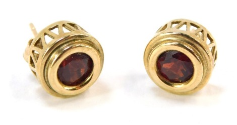 A pair of 9ct gold garnet earrings, of circular design on raised and pierced basket, stamped 375, with single pin back and butterfly backs, 2.6g all in.