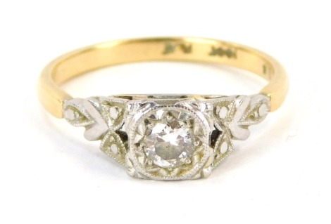 A diamond solitaire ring, the central illusion set round brilliant cut diamond approximately 0.15ct in a raised square setting, with fan design shoulders in platinum, on a yellow metal band marked 18ct plat, size M½, 2.7g all in.