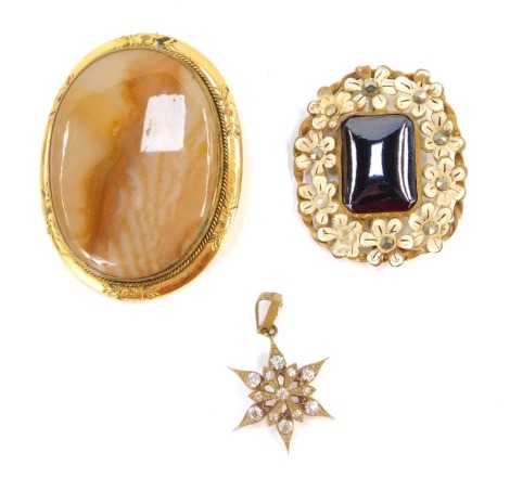 A group of Edwardian and later jewellery, comprising an agate and Pinchbeck framed oval brooch, 5.5cm wide, an enamel flower and marcasite brooch, 4.5cm wide, and a brass and paste stone set star pendant, 4cm high. (3)