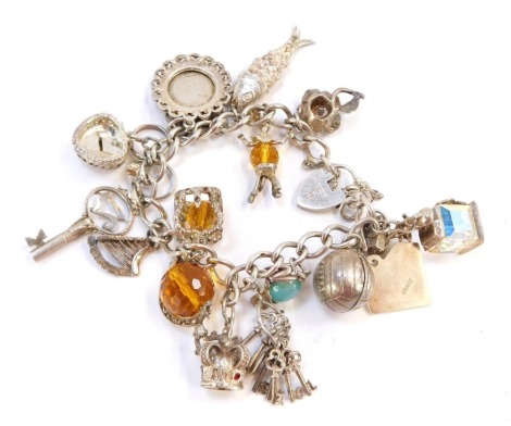 A silver charm bracelet, the curb link chain with heart shaped padlock and safety chain with a selection of charms, some stamped 925 others unmarked, comprising rose, fish, clown, horse shoe, trinket box, twenty one key, engagement ring, spinning globe, h