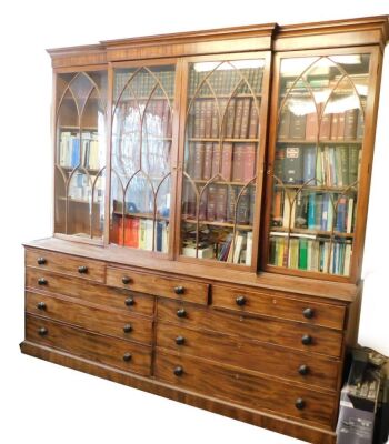 An early 19thC flamed mahogany break front cabinet and secretaire bookcase, with moulded cornice, Gothic arch astragal glazed doors to upper part, the lower having a combination of drawers, including a fitted central secretaire section with six compartmen