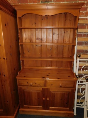 A pine dresser with open rack, with lower drawers and cupboards.