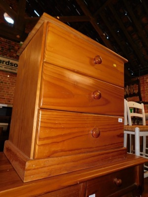 A pine bedside chest of three drawers.