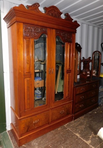 A Victorian walnut double wardrobe and dressing chest, by Blair and Kemp, Horncastle, the wardrobe with outswept pediment over a pair of carved and mirror set doors, the doors opening to reveal hanging hooks over a pair of deep drawers raised on a plinth