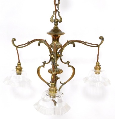 A Victorian brass three branch electrolier, the scroll supports, on chain hanging, with fluted frilled glass shades, 61cm high.