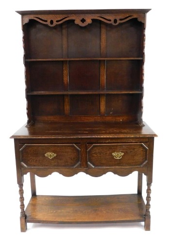 An early 20thC oak dresser, the dresser plate top with pierced and carved frieze over two shelves, above two drawers, on ring turned legs united by an under tier, 194cm high, 121cm wide, 45cm deep.