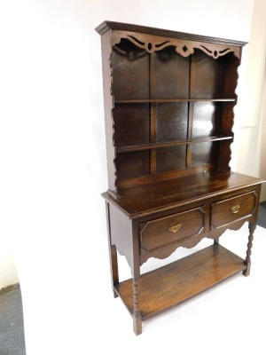 An early 20thC oak dresser, the dresser plate top with pierced and carved frieze over two shelves, above two drawers, on ring turned legs united by an under tier, 194cm high, 121cm wide, 45cm deep. - 2