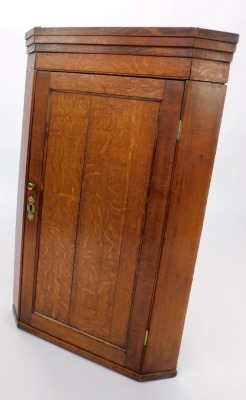 A 19thC oak hanging corner cupboard, the pediment above a single panelled door, with brass handle and escutcheon, enclosing three shelves, 102cm high, 68cm wide, 39cm deep. - 2