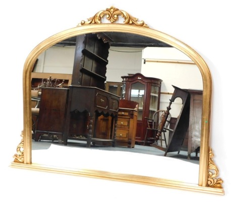 A Victorian style gilt framed oval mantel mirror, the arched top with foliate detailing, 106cm high, 140cm wide, 7cm deep.